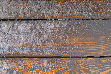 Frozen yellow-gray horizontal wooden planks covered with a layer of frost and grains of snow. Flat lay.