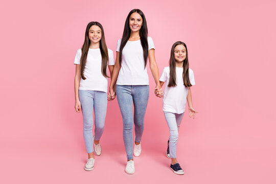 Full Length Body Size Photo Of Mother Holding Hands Daughters Walking Forward Smiling Isolated Pastel Pink Color Background