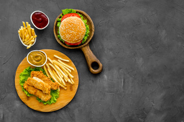 Fast food set. Delicious burger with french fries on wooden cutting board