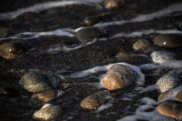 Sea shore with stones and foam, pebble seascape. 