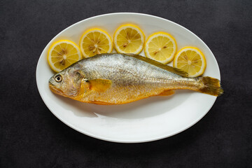 A fresh yellow croaker on a white plate