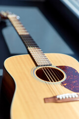 Naklejka premium leisure, music and musical instruments concept - close up of acoustic guitar on window sill