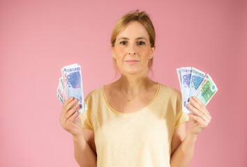 Young woman holding bank notes isolated over pink background