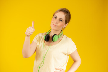 Smiling pretty young woman showing thumb up isolated over yellow background