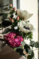 Spring bouquet with white anemones, pink ranunculus and eucalyptus .