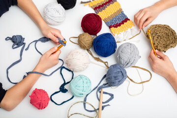 Children's hands are crocheted and thread. View from above