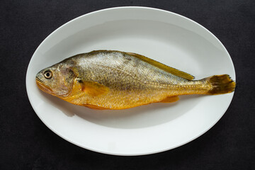 A fresh yellow croaker on a white plate