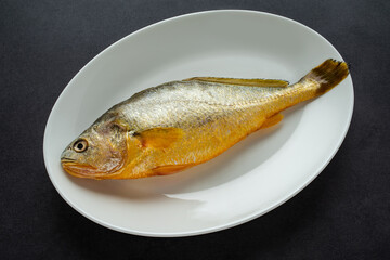 A fresh yellow croaker on a white plate
