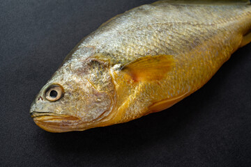 A fresh yellow croaker on a black background