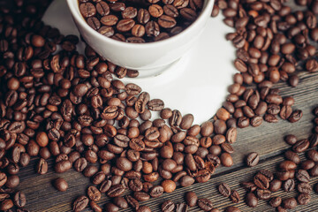 coffee beans on a wooden background and a cup on a saucer close-up macro photography