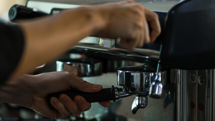 Close up shot of glass cup filled with hot delicious good smell black coffee made by barista hand from luxury coffee making machine in cafe with blurred foreground and background