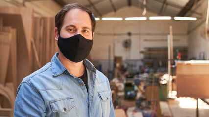Fototapeta na wymiar Young man as a craftsman trainee with face mask
