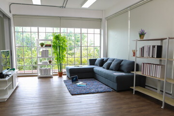 Cozy comfortable fully decorated white living room with wooden floor brightens by natural sunlight included furniture such as sofa pillows television bookshelf tree pot carpet laptop © Bangkok Click Studio