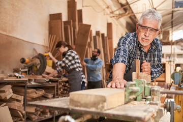 Senior craftsman as a carpenter planing wood - obrazy, fototapety, plakaty