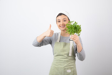 Portrait of a pretty cute woman with beam of fresh parsley showing a thumb up