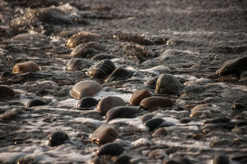 Sea shore with stones and foam, pebble seascape. 