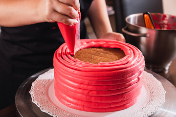 Woman decorating delicious cake with fresh cream on stand. Homemade pastry.