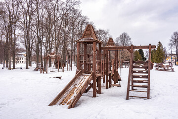 Fototapeta na wymiar Children playground in the public park. Wooden constructions from fairy tale scenes. Winter sketch.