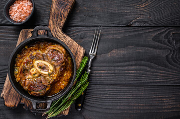 Stew veal shank meat OssoBuco,  italian osso buco steak. Black wooden background. Top view. Copy space