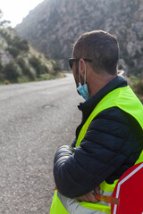 Road maintenance worker during the coronavirus pandemic, on a road with a stop sign and reflective vest