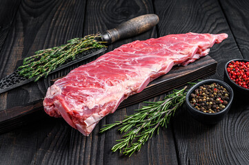 Raw veal calf short spare rib meat with butcher knife. Black wooden background. Top view