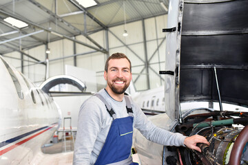 Portrait of an aircraft mechanic in a hangar with jets at the airport - Checking the aircraft for safety and technical function © industrieblick