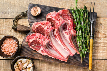 Lamb raw cutlets chops  with salt, pepper and garlic. wooden background. Top view