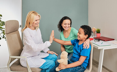 Child psychologist gives five an African American boy during a psychotherapy session