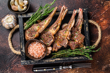 Grilled lamb chops steaks in a wooden tray. Dark background. Top view