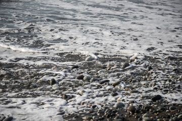 Sea shore with stones and foam, pebble seascape. 