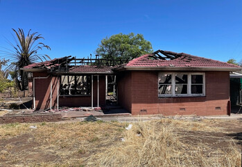 Red brick house burnt out by fire blackened frame from arson attack