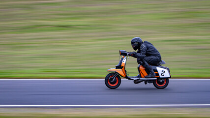 Fototapeta premium A panning shot of a racing moped as it circuits a track.