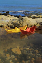 Paper boats in puddle on the rocky beach near village of Beer in Devon