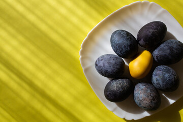 Easter eggs on a plate on yellow background. Place for text. Happy Easter 2021.
