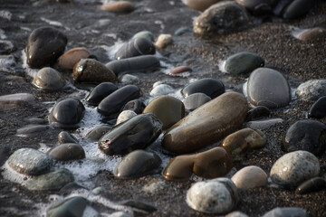 Sea shore with stones and foam, pebble seascape. 