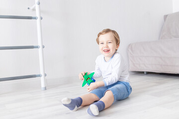 happy baby boy plays at home with an airplane and laughs