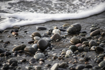 Sea shore with stones and foam, pebble seascape. 