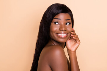 Photo of interested positive cute lady hand touch cheekbone look empty space toothy smile isolated beige background