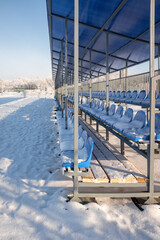 plastic seats in a football stadium covered with snow in winter