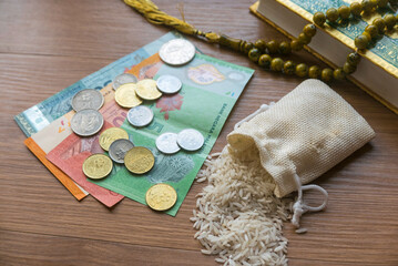 Concept of zakat in Islam religion. Selective focus of money, rice, rosary beads and Quran on...