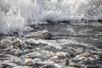 Sea shore with stones and foam, pebble seascape. 