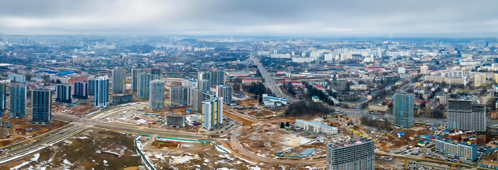 Fototapeta na wymiar Panoramic view of construction of high-rise resedential buildings. The construction industry with working equipment. View from above. Eye bird view of new resedential district.