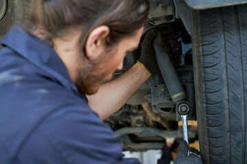 Fototapeta na wymiar The Mechanic male repair the suspension of car on hydraulic lift
