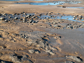 Clay exposed under sand, coastal erosion after bad weather. UK.