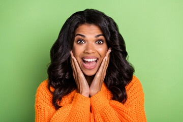 Fototapeta premium Photo of excited crazy lady palms cheekbones open mouth wear orange jumper isolated green background