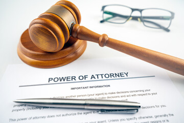 power of attorney text on contract with pen, gavel and glasses as props.
