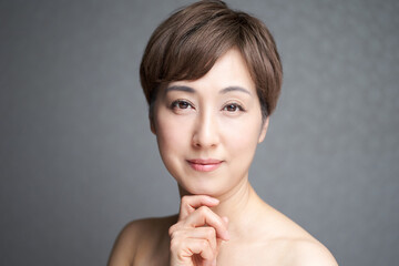 Obraz na płótnie Canvas カメラ目線で顎に手を当てる中年の日本人女性