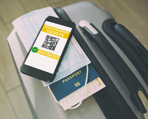 Mobile phone on the suitcase and health passport of vaccination certification on the screen
