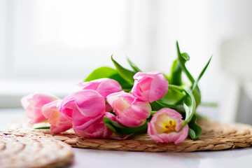 Beautiful bouquet of pink tulips on a white table. Spring present for a girl. Flowers, spring holidays and home decor concept.