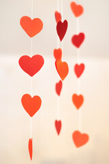 Paper red decorative hearts hang on a thread.